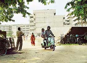 A scooterist comes out of the unauthorised passage in the boundary wall