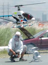Miniature remote-controlled helicopters hover above ground as a hobbyist (background) prepares to launch his aircraft for a fun fly in Manila