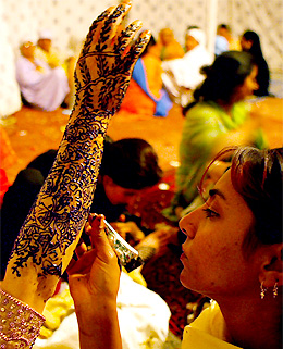 A girl applies henna on the arm of a Kashmiri Muslim bride on her Manzi Raat