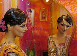 A model and Bollywood star Roshni Chopra looks in the mirror after getting a bridal makeover at the Bridal Asia 2004 exhibition in New Delhi
