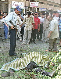 Iraqi policemen survey the scene of a mortar attack