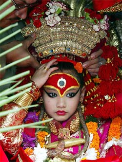 Kumari, believed by Nepalese to be a living goddess, adjusts her headgear