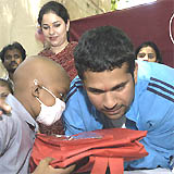 Test cricketer Sachin Tendulkar interacts with a young cancer patient in Mumbai on Wednesday. Tendulkar and his wife Anjali (behind) distributed gifts and spent time with the cancer patients. 