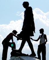 Men clean a statue of Mahatma Gandhi on the eve of the 135th birth anniversary of the Father of the Nation