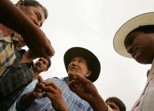 Japanese-born emerald exporter Eishy Hayata, surrounded by his bodyguards, inspects gems held by miners who want to sell their precious stones, near a mine in Coscuez, province of Boyaca. 