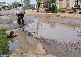 A man rides a cycle on the Mubarikpur-Neembuan village link road full of potholes.
