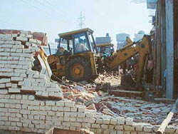 A structure on the Shivpuri Road being demolished by Municipal Corporation staff on Thursday.
