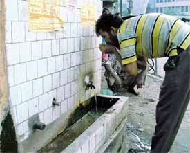 Thirst forces this man to drink from a roadside tank
