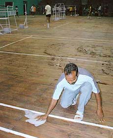A worker cleans up a badminton court on the eve of the National Sub-Junior Badminton Championship at Sector 42 badminton hall