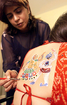 An artist decorates a womans back for the Navratri festival in Ahmedabad on Sunday.
