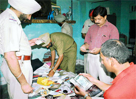 Policemen examine belongings of the person who was found murdered near Shiv Puri in Ludhiana 