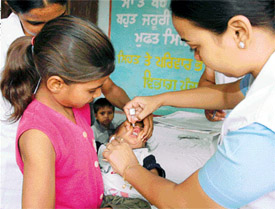 A sister helps her brother to get polio drops at a booth in Ludhiana 