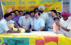 Mr R.K. Dudeja, Manager, State Bank of Patiala, Doraha, administers polio drops to a child