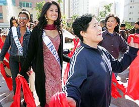 Miss Ethiopia Helena Mezegbu (left) Miss India Mihika Varma (centre) dance with a group of Chinese folk dancers during a visit to a residential complex in Beijing on Tuesday. The Miss International Beauty Pageant final will be held in Beijing on Saturday.