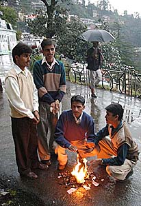 People warm their hands as cold winds sweep Shimla