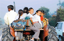 Schoolchildren, unmindful of the danger, travel on a tractor. Accidents have been reported when children travelling in such a manner have fallen off and injured