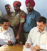 Proclaimed offender Kimti Lal Jain (left) in custody of the police. 
