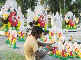 An artisan gives finishing touches to an idol of Goddess Durga in Ludhiana