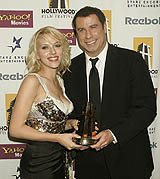 ctor John Travolta along with presenter/actress Scarlett Johansson poses with his Lifetime Achievement Award