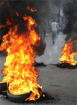 A Kashmiri shopkeeper walks past burning tires during a protest