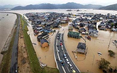 The Yura river, with its collapsed embankments, overflows into roads and homes in the western Japanese city of Maizuru 