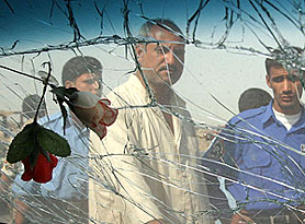 Plastic roses hang inside a damaged car at the site of a roadside bomb attack 