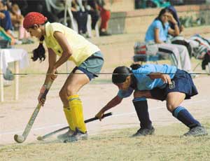 Sandeep Kaur of KCW, Ludhiana, being checked by a player of GGS College for Women, Sector 26, during the Panjab University Inter-College Hockey (Women) Tournament in Chandigarh on Tuesday.