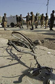 Soldiers stand near a cycle destroyed in an explosion in Srinagar on Friday. 