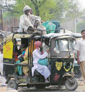 In the absence of regular buses, people travel in and on top of autorickshaws 