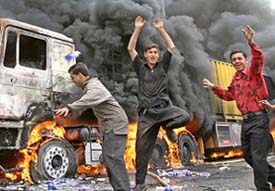 Iraqi youths chant anti-US slogans near one of four burning trucks following an attack in the northern city of Mosul on Saturday. The trucks were carrying supplies to a nearby military base.