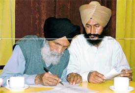 Amrik Singh signs a statement in front of mediapersons while his son Jatinder looks on in Ludhiana
