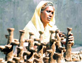 A potter gives the finishing touches to a diya in Qilla Mohalla on Monday