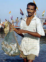 A fisherman carries a net full of fish ashore as fishing boats return to Colaba fishing village, early morning in Mumbai on Sunday. 