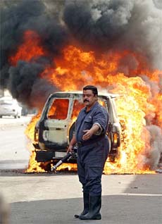 A firefighter arrives at the scene of a burning vehicle after it came under attack by unknown gunmen in the centre of Baghdad on Sunday