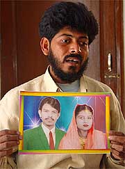  Shahid Noor, an orphan of the Bhopal gas tragedy, holds out portraits of his parents who died immediately after inhaling the toxic gases on the night of December 2, 1984.  