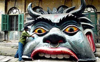 An artist gives final touches to a demon-shaped pandal ahead of Kali Puja