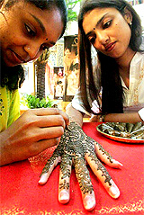 A girl has her hand painted with mehendi ahead of Divali