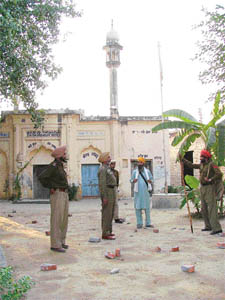 Cops stand beside stones pelted by members of a community at a religious place in Bhaura village