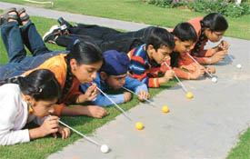 Children of Chanda Mama Kids Club push ping pong balls with straws at a function in Ludhiana