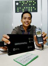 De La Salle University student Miguel Pascual shows off an invention in Manila on Sunday by his school group, which allows cellphone SMS or text messages to be converted to Braille form so that such messages can be read by the visually challenged. 