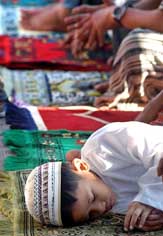 A child sleeps as devotes pray ahead of Id in Zamboanga, southern Philippines, on Sunday