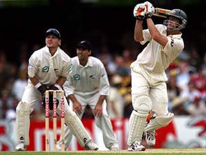 Australias Adam Gilchrist hits a six as New Zealands Brendon McCullum (L) and Stephen Fleming look on during the third days play of the first Test in Brisbane on Saturday.