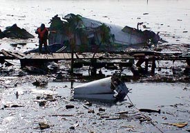 A Chinese rescuer searches the wreckage of a plane on a lake