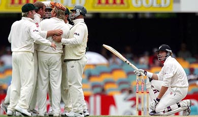 New Zealands Jacob Oram kneels beside the stumps as Australian team members celebrate his dismissal on day four of the first Test in Brisbane
