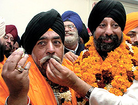 Ravinder Khurana offering sweets to Paramjit Singh Sarna after the DSGMC elections in the Capital on Monday