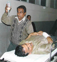 A relative attends to Mr Ram Parkash Bharti, who was shot at and injured by robbers in his shop in Ghumar Mandi in Ludhiana on Monday