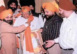 Paramjeet Singh Pamma, leader of National Akali Dal and president of Sikh Welfare Society, Satpal Singh Manga (R) presenting a Saropa and a photo of Guru Nanak Devji to the President in the Capital.