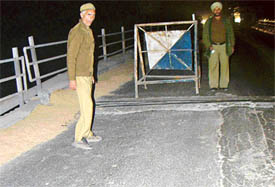 Policemen guard a damaged span of the Ghaggar bridge on the Kalka-Ambala road