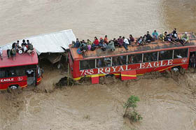 Passengers wait atop a bus after being stranded by flash floods caused by typhoon Winnie in Gapan
