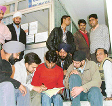 Duped youngsters gather outside the office of the Global Infosys company in Ludhiana on Friday